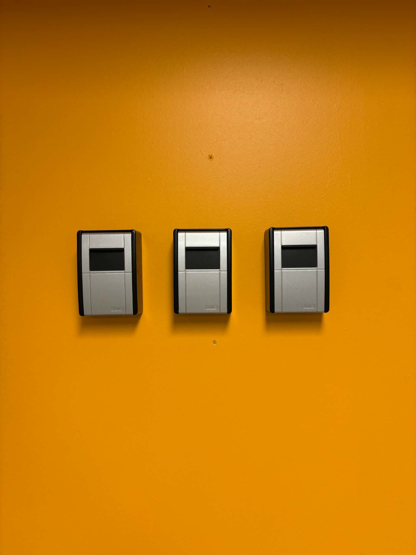 Three key boxes mounted on the orange wall at Tromsø Luggage Storage